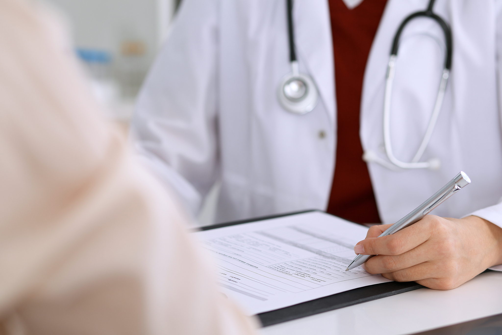 close up of a female doctor filling up  an application form whil