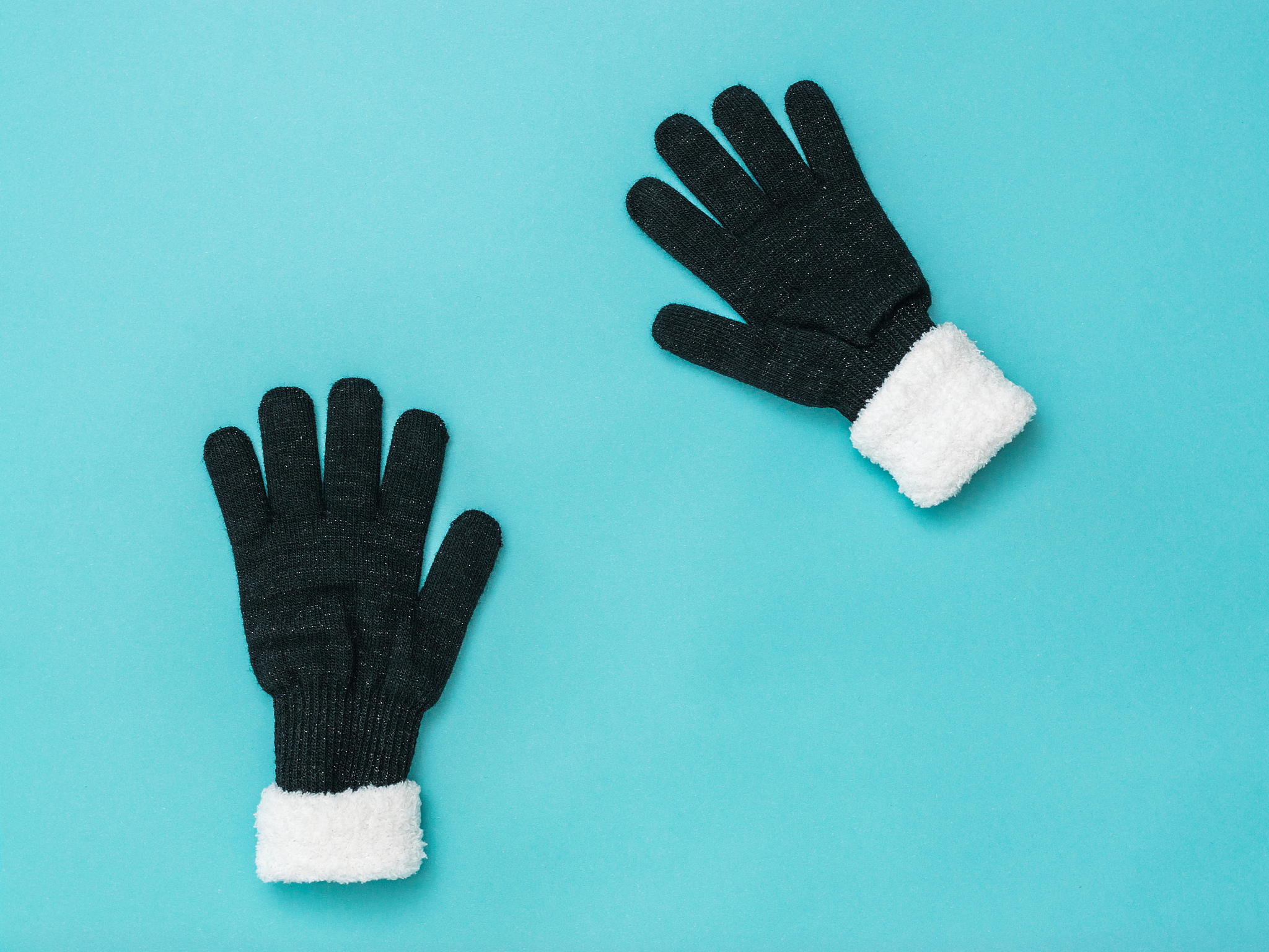 two knitted black women's gloves on a blue background. flat lay.