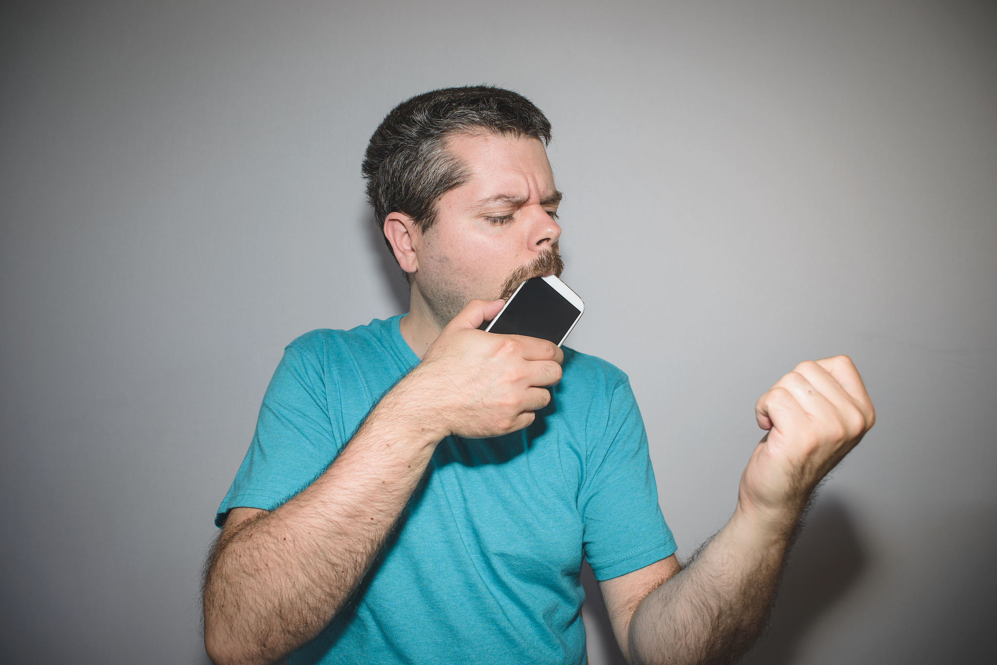 man biting and chewing on his smart phone