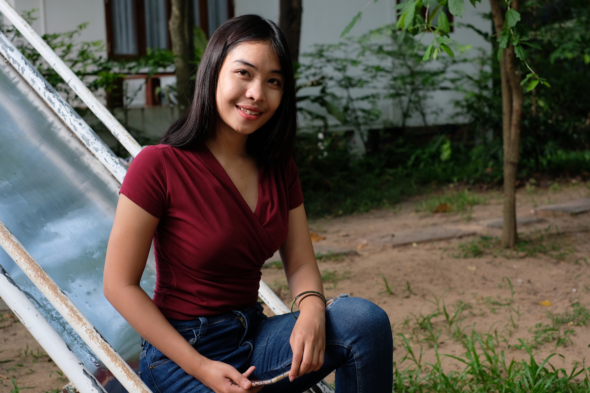 portrait of smiling young woman sitting on slide in park