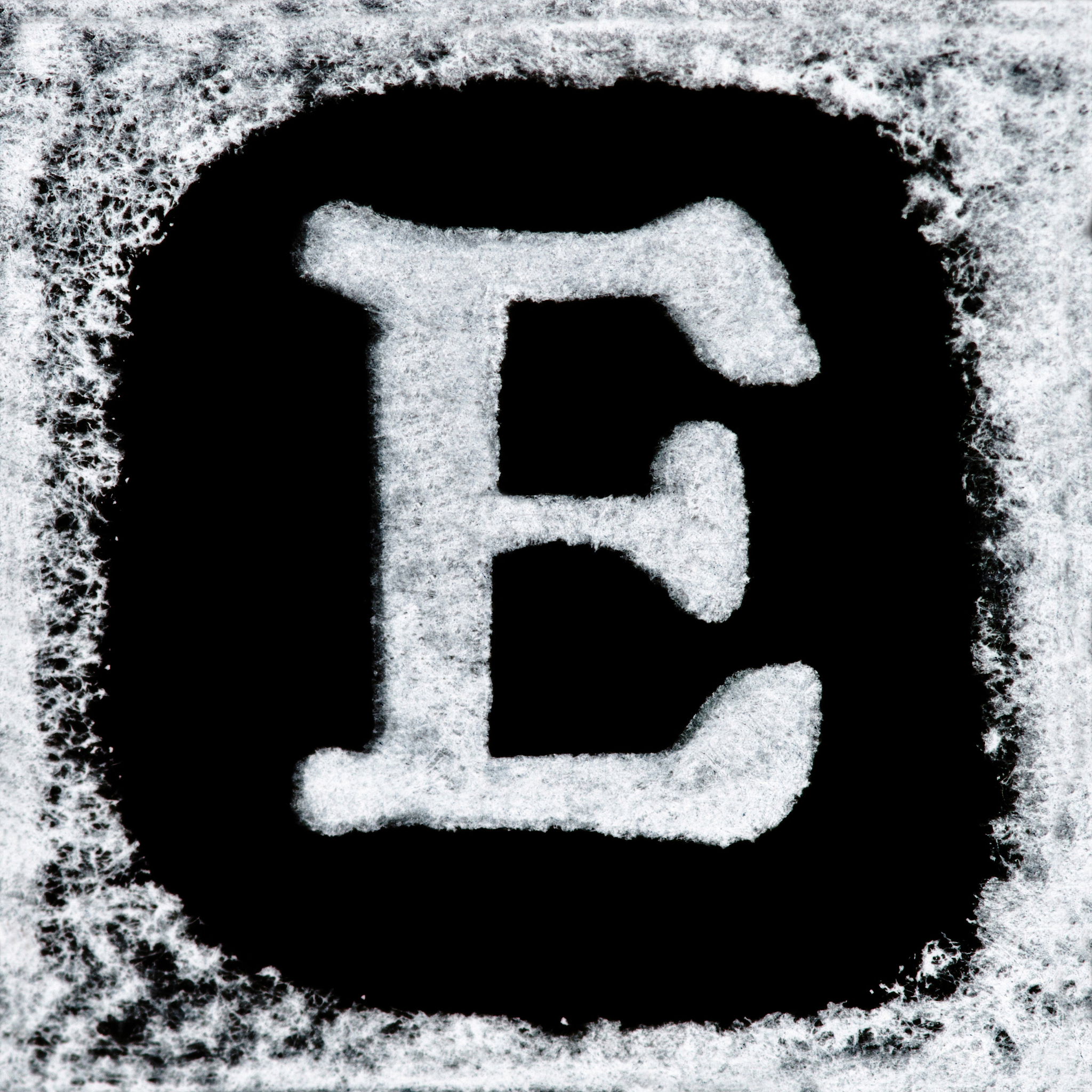 english capital letter 'e' printed white ink stamp isolated on b