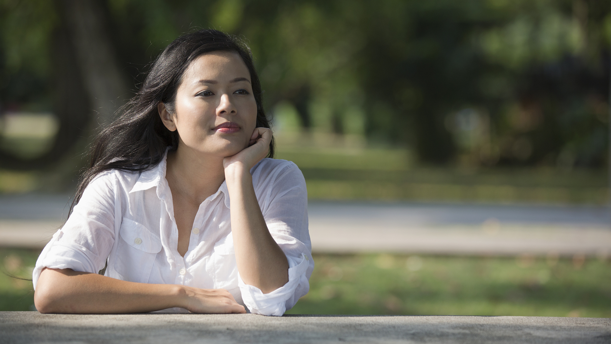 young woman siting outdoors thinking.