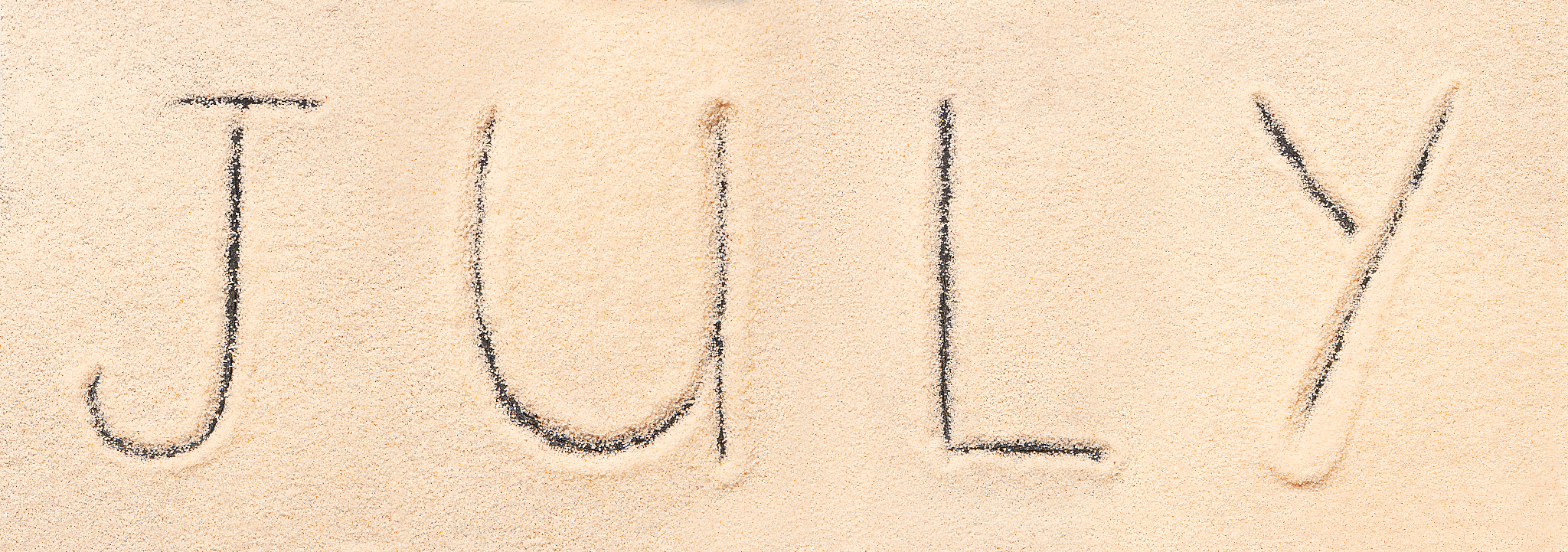 july lettering drawn on sand