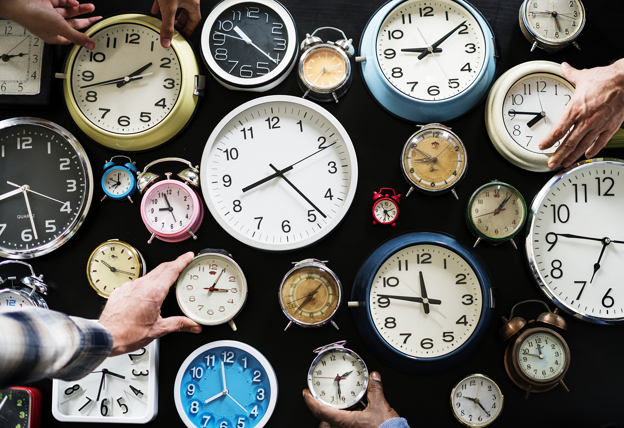 closeup of hands holding clocks
