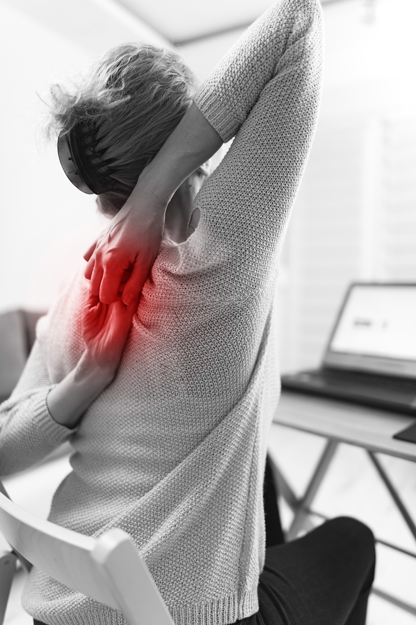 woman working on a laptop and having hand, back, spine pain.