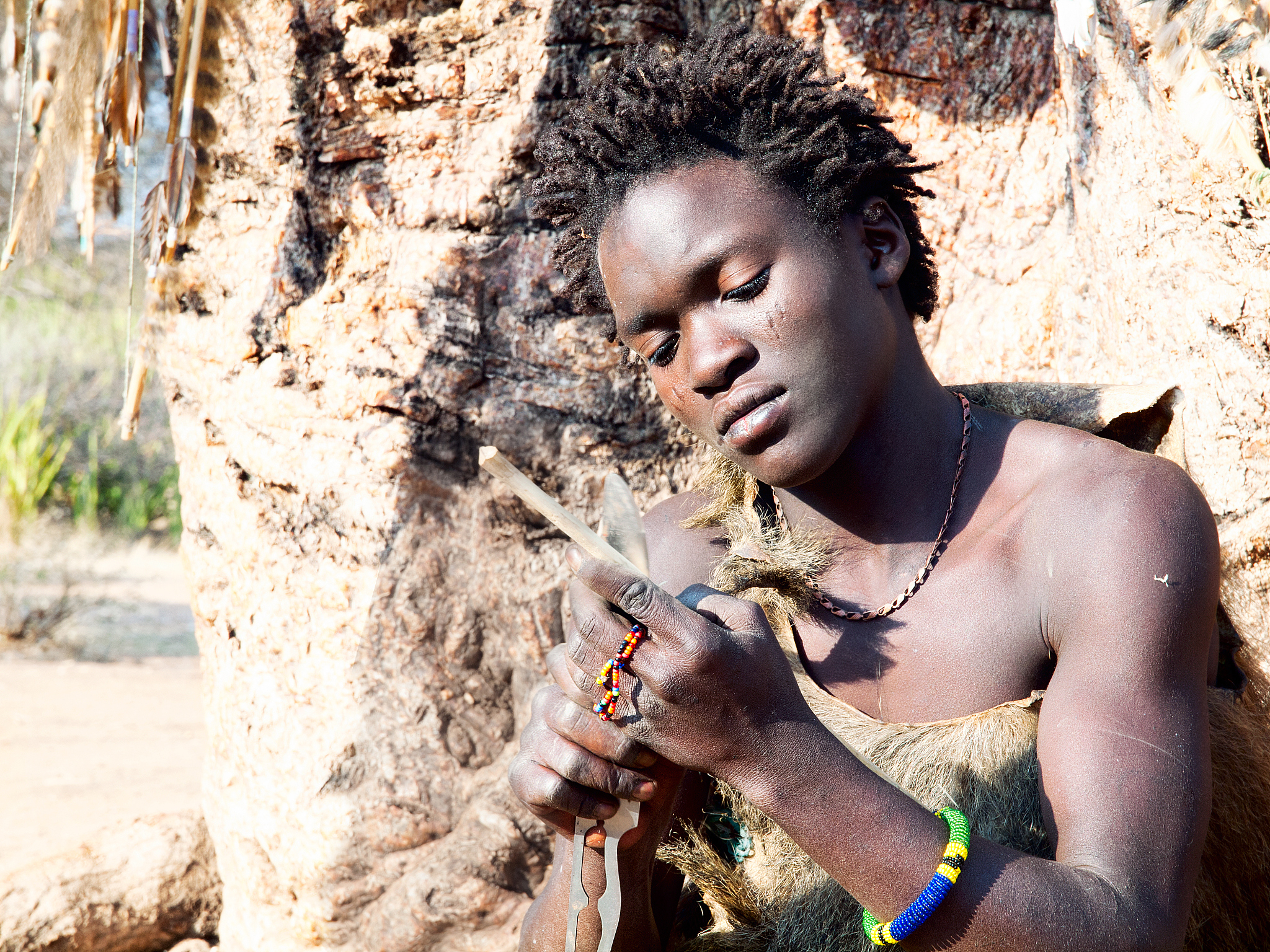 hadzabe young bushman making the arrow for a hunting bow