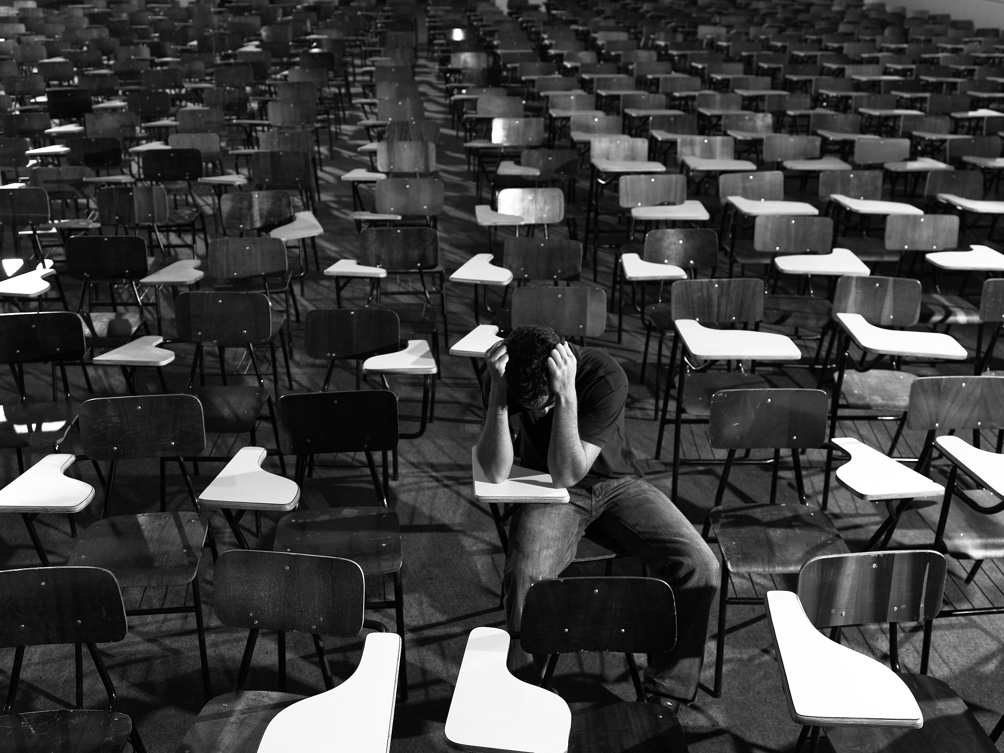 student in class holding head in hands (b&w)
