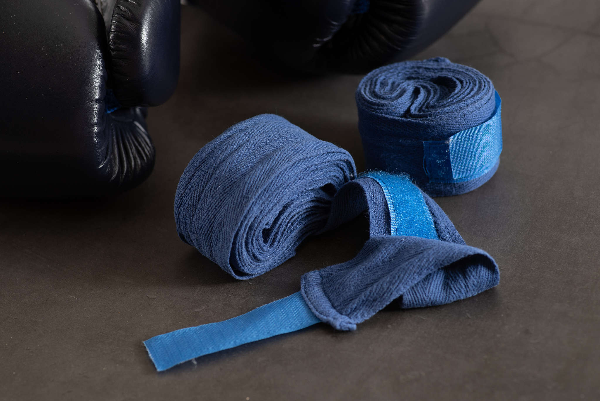 navy blue boxing gloves and a pair of boxer hand wraps on an ind