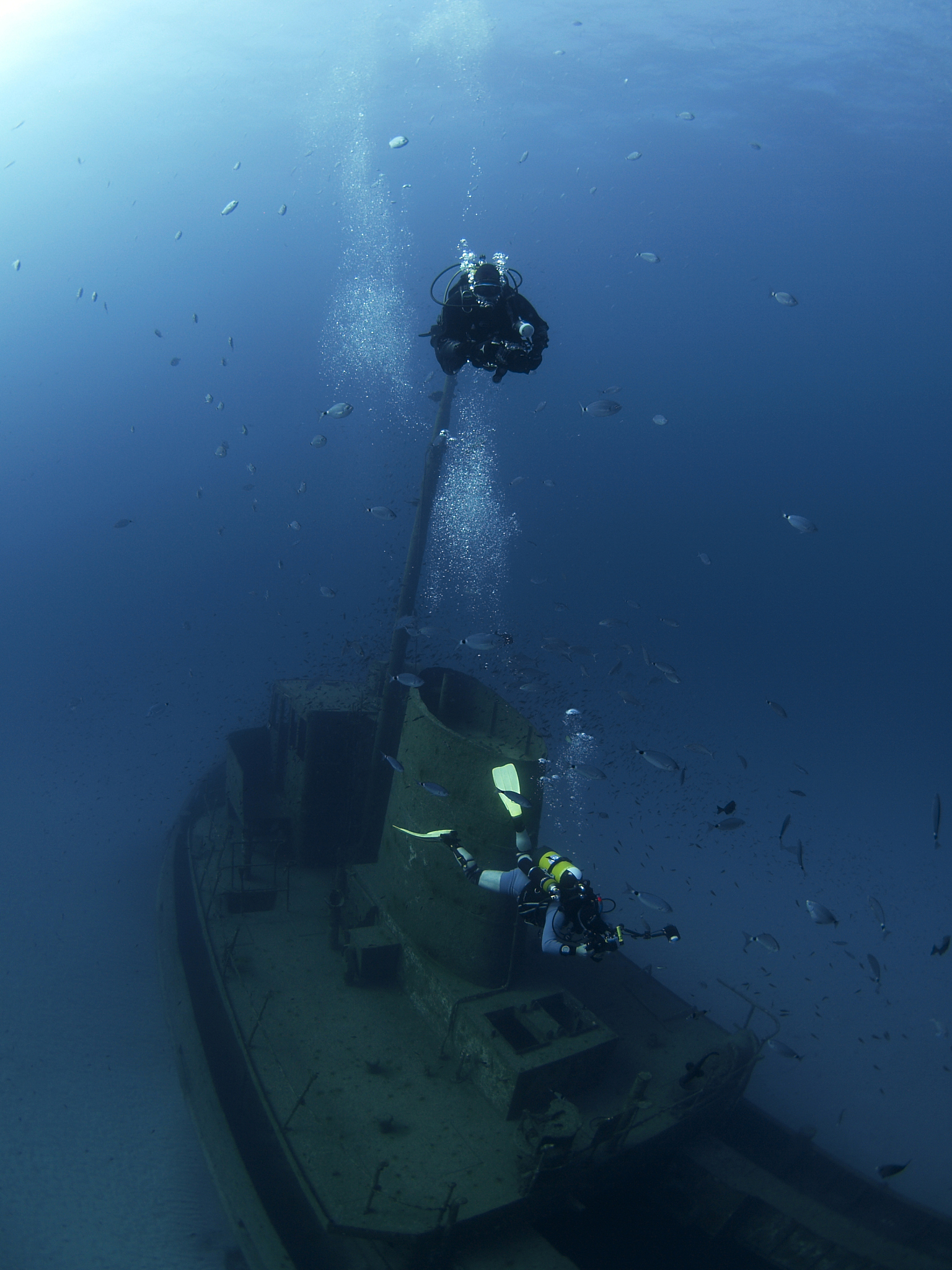 scuba divers taking photos of a shipwreck