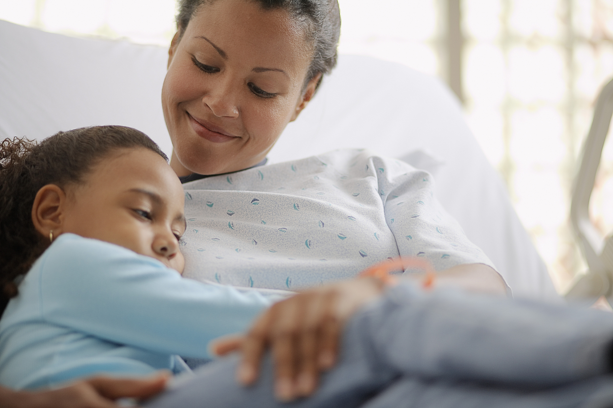 mother comforting daughter in hospital bed
