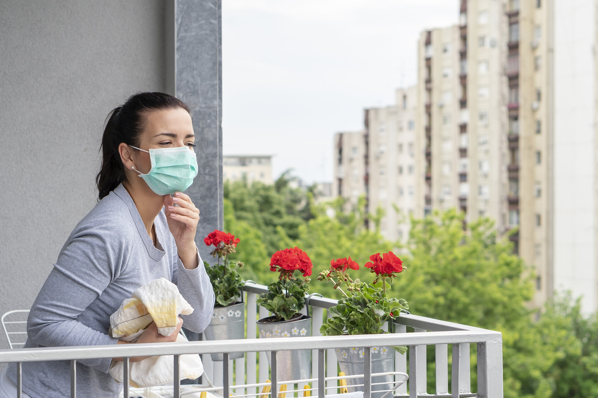 young woman with allergy hanging wet clothes to dry  on balcony