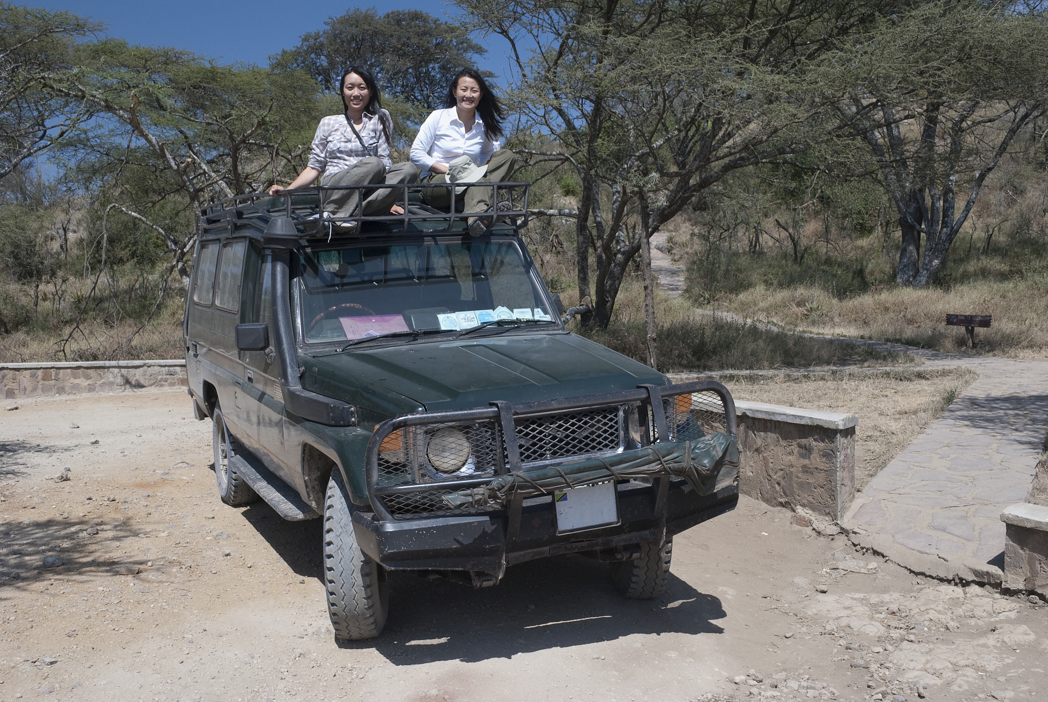 two chinese women sitting on car in serengeti