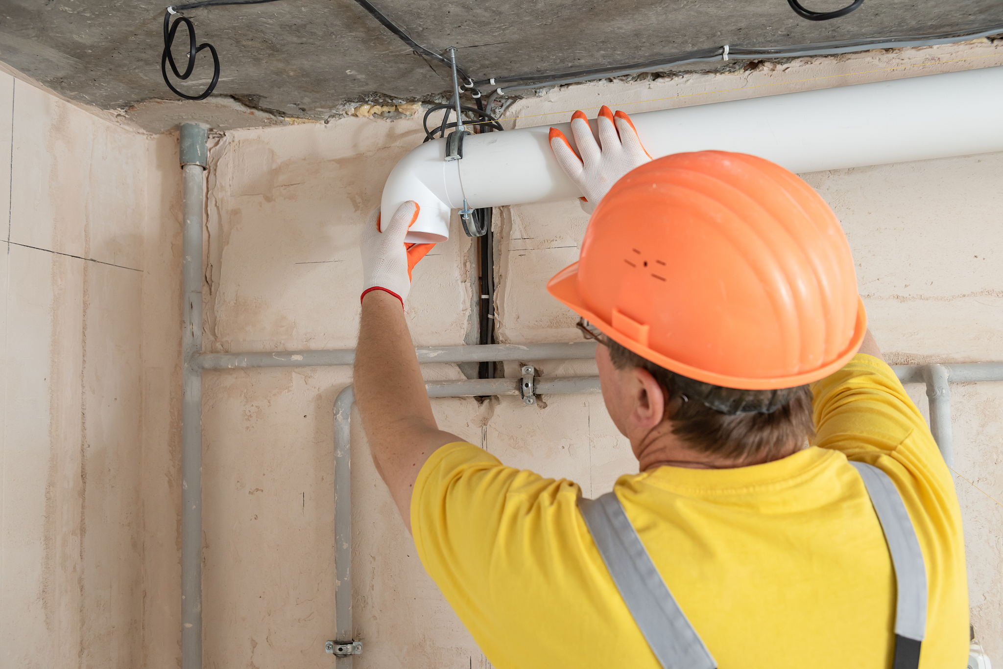 the worker is installing a ventilation system.
