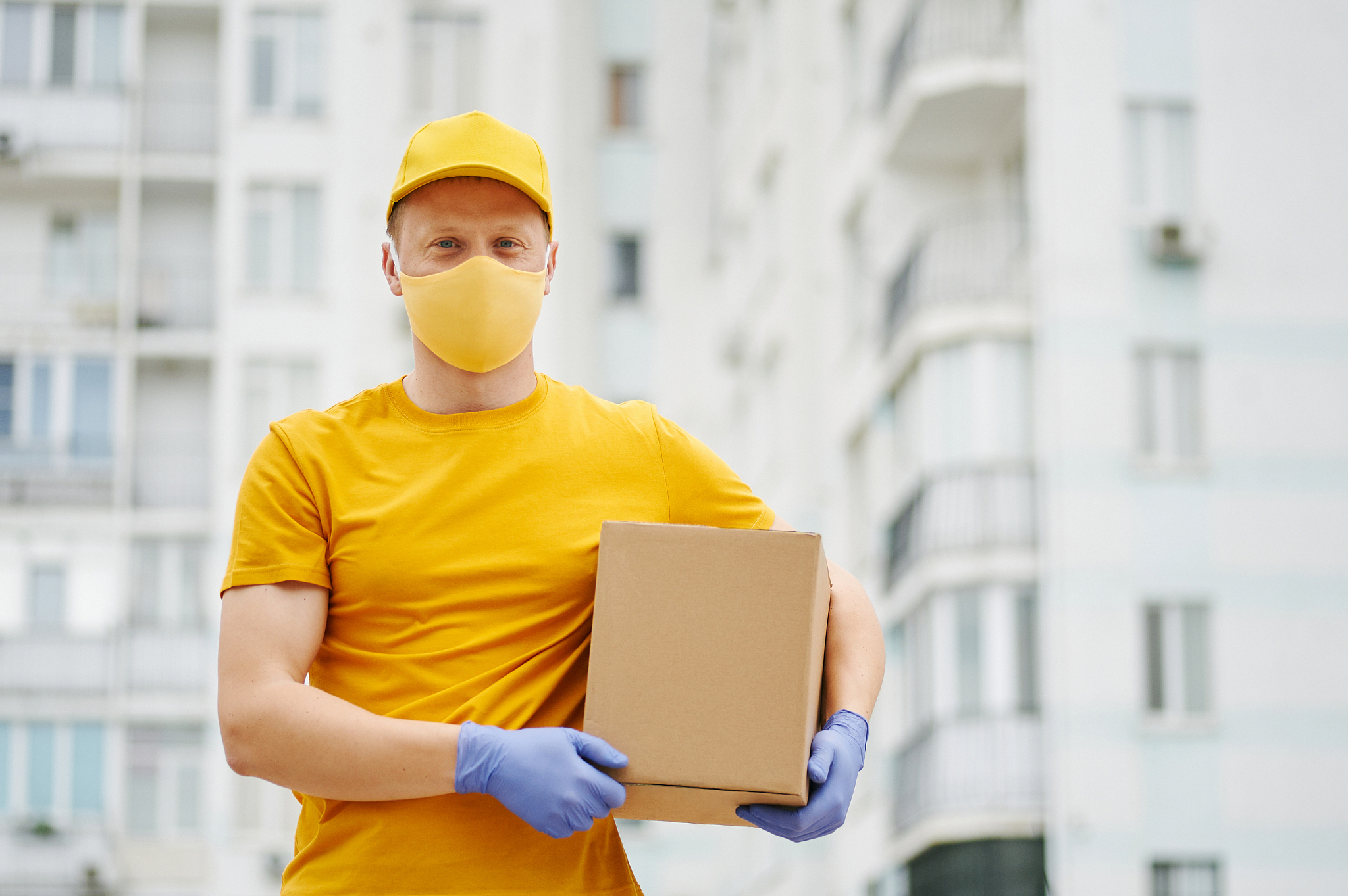 delivery man employee in yellow uniform cap, t-shirt, face mask 