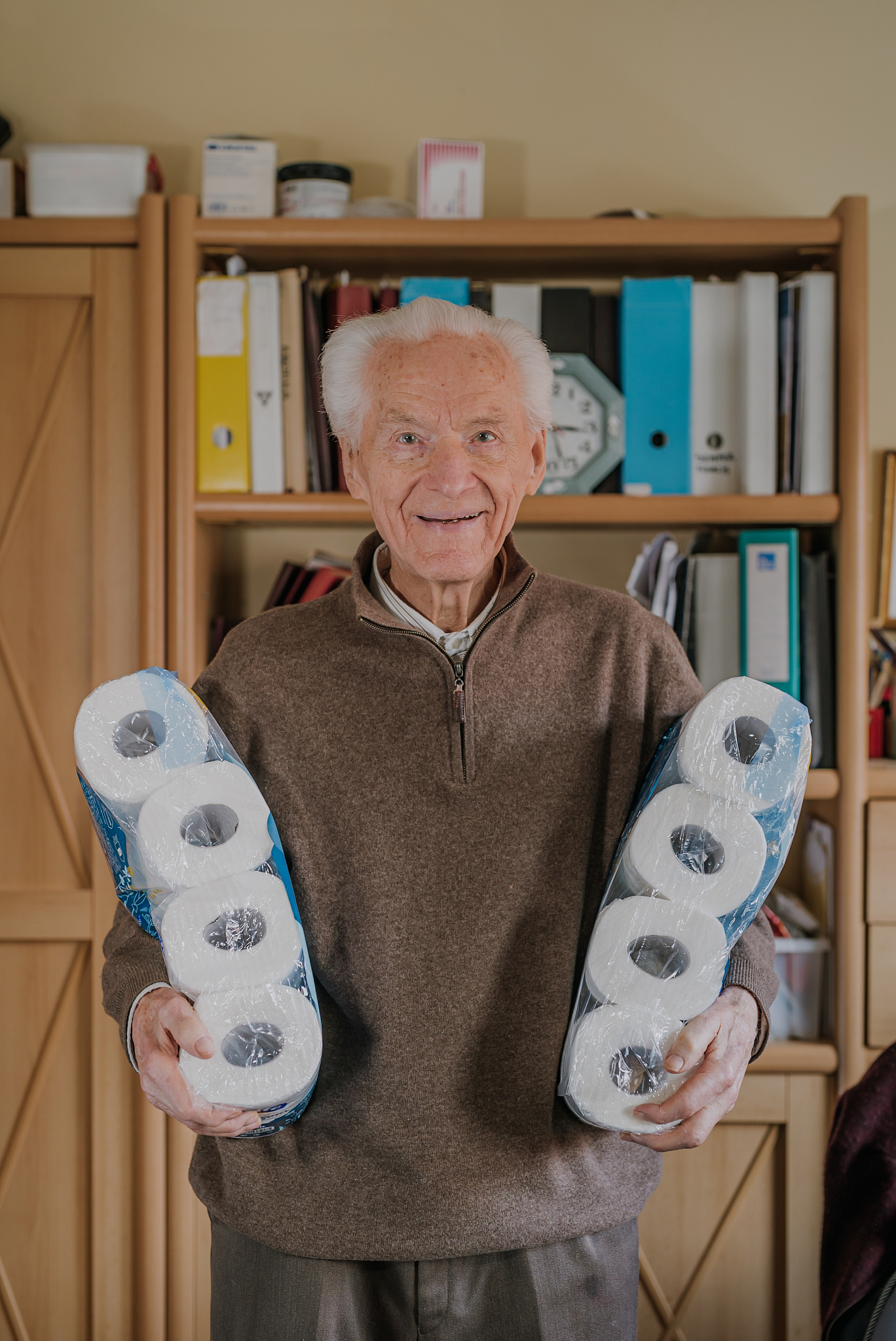 old man holding two packs of toilet paper