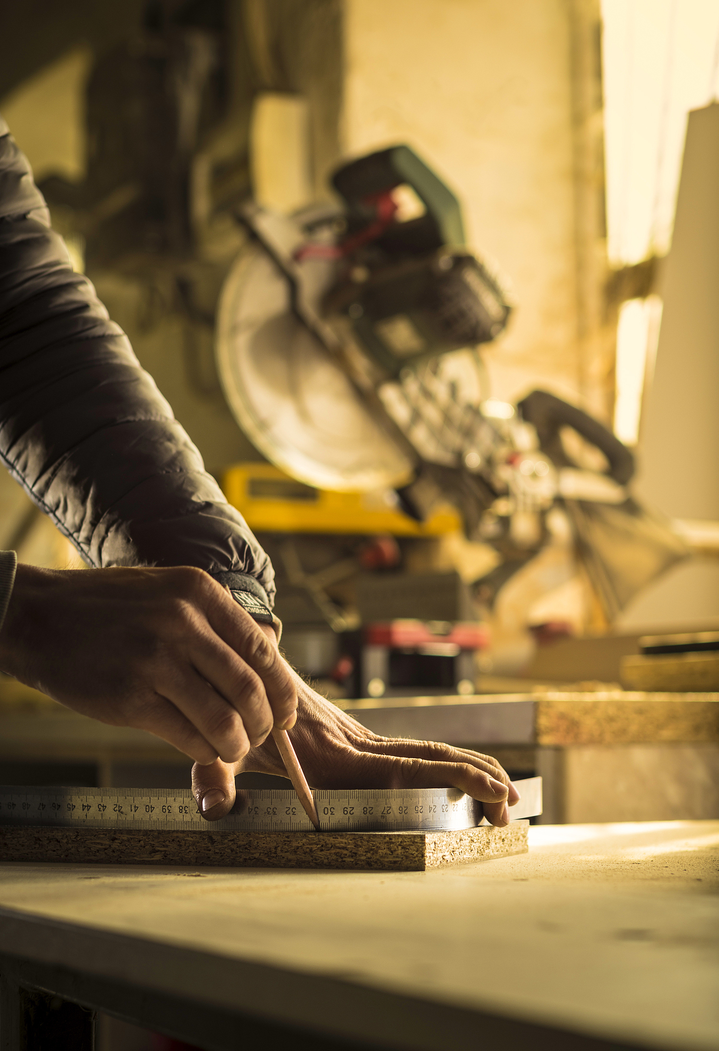 young carpenter drawing corners of a wooden board for furniture