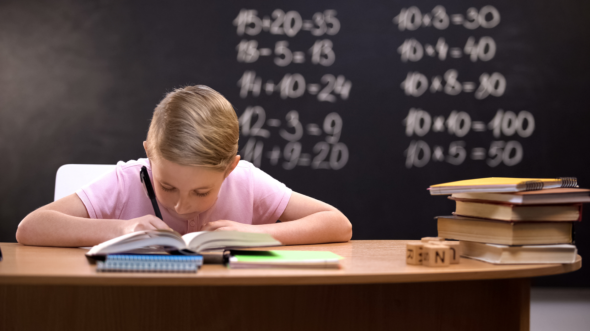 smart schoolboy solving task, math exercises written on blackboa