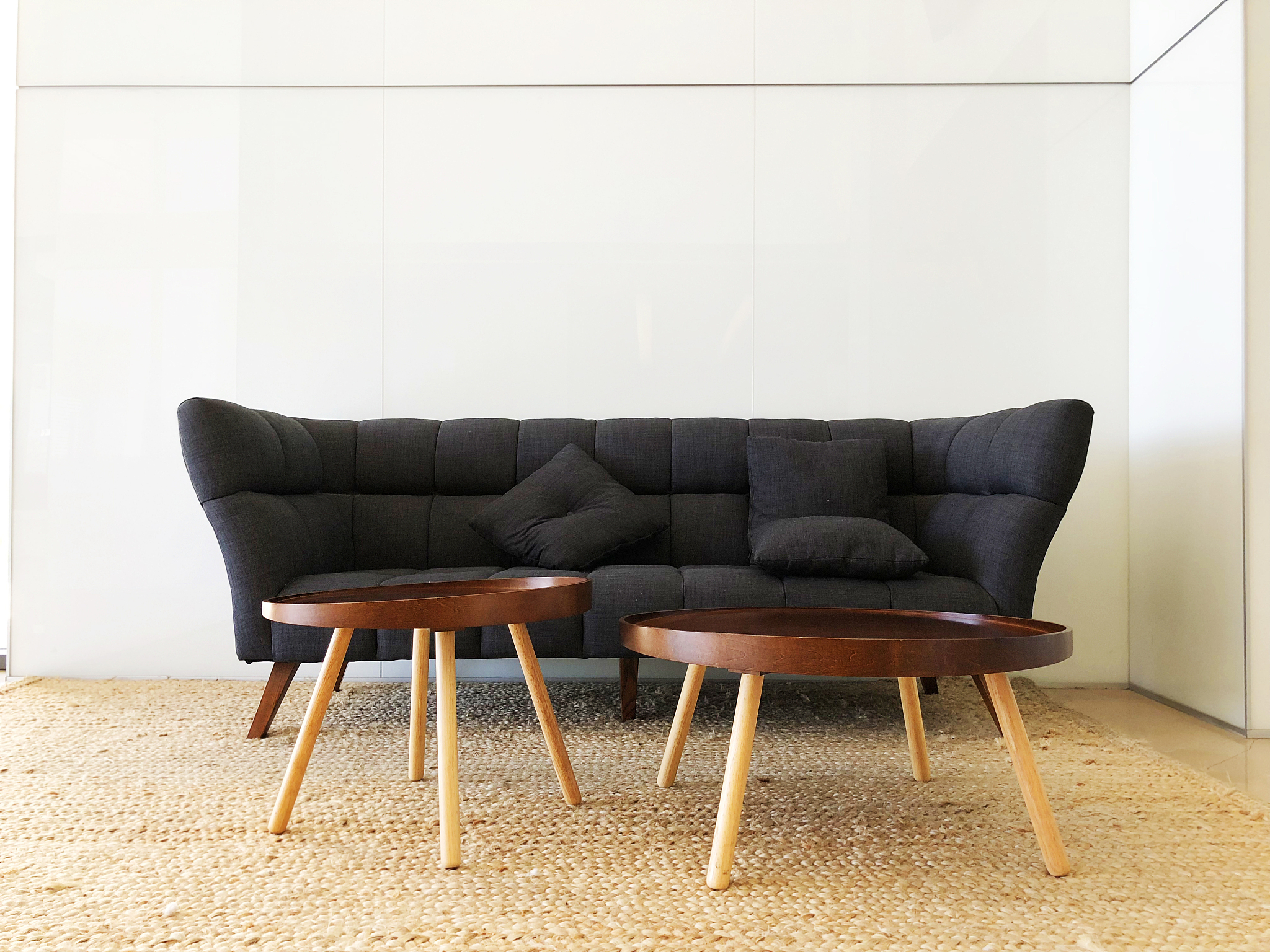panorama of living room with black sofa, round tables.