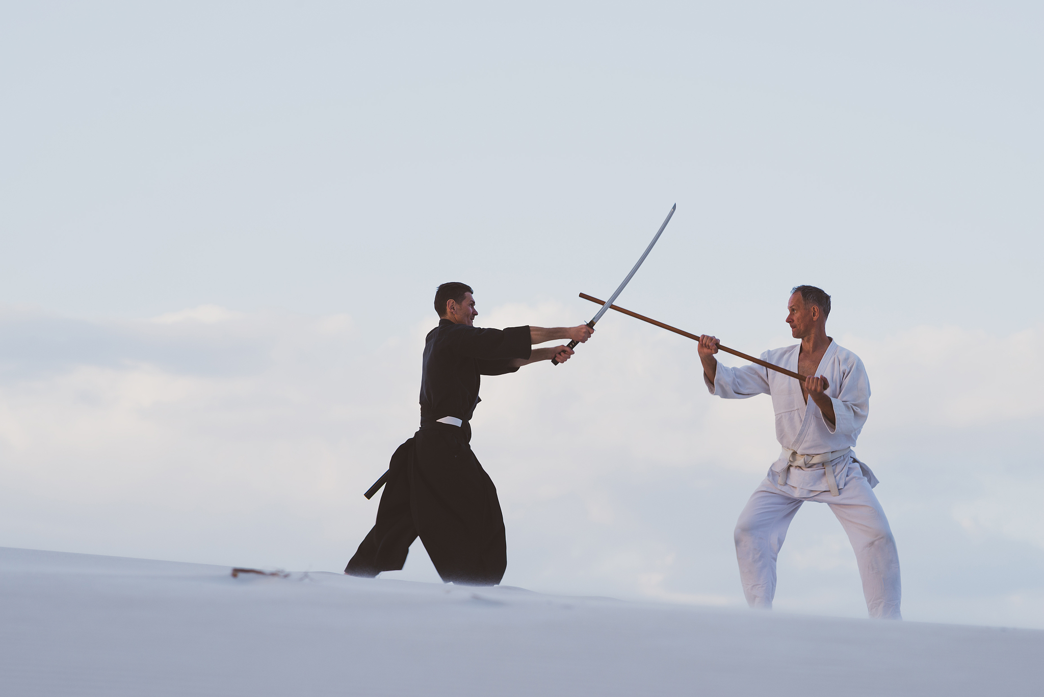 two men practicing japanese martial arts in desert