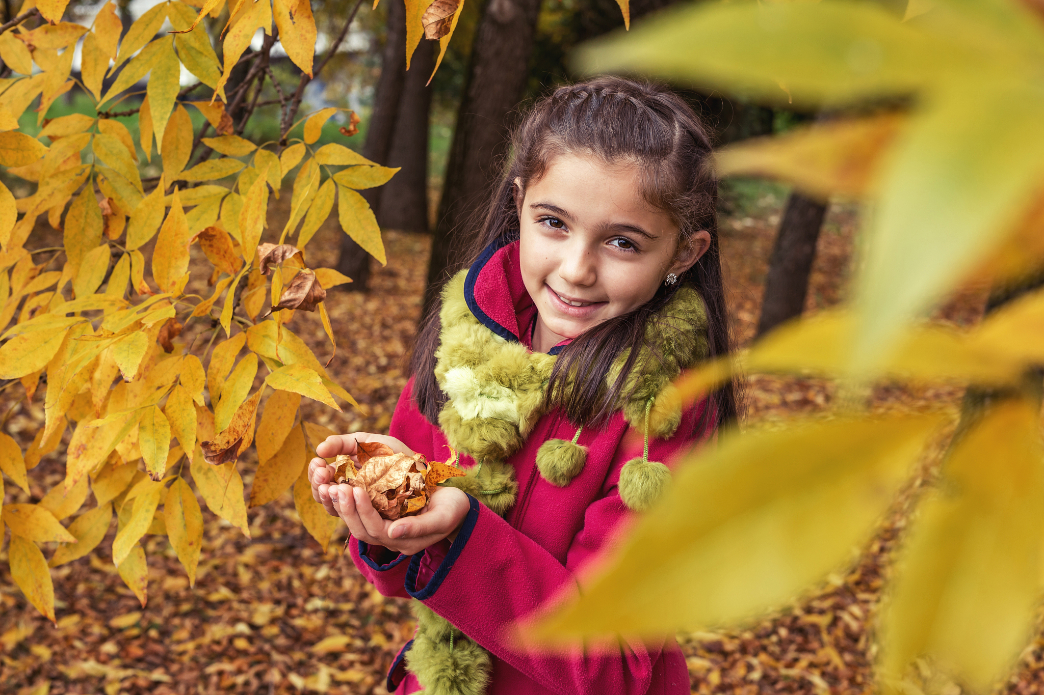 adorable teenage girl in nature with dry leaves in hands