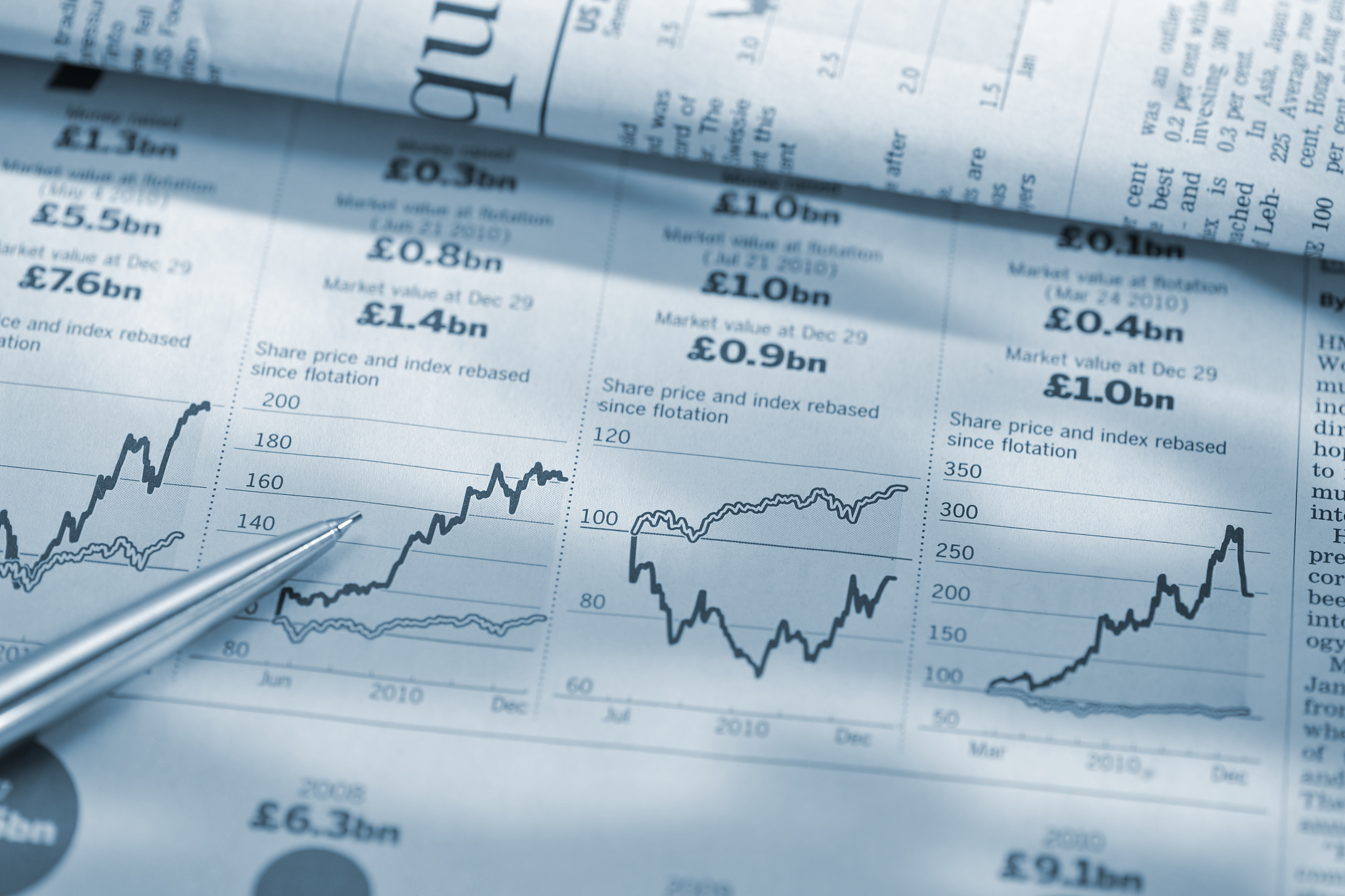 pen on stock price graphs in financial newspaper