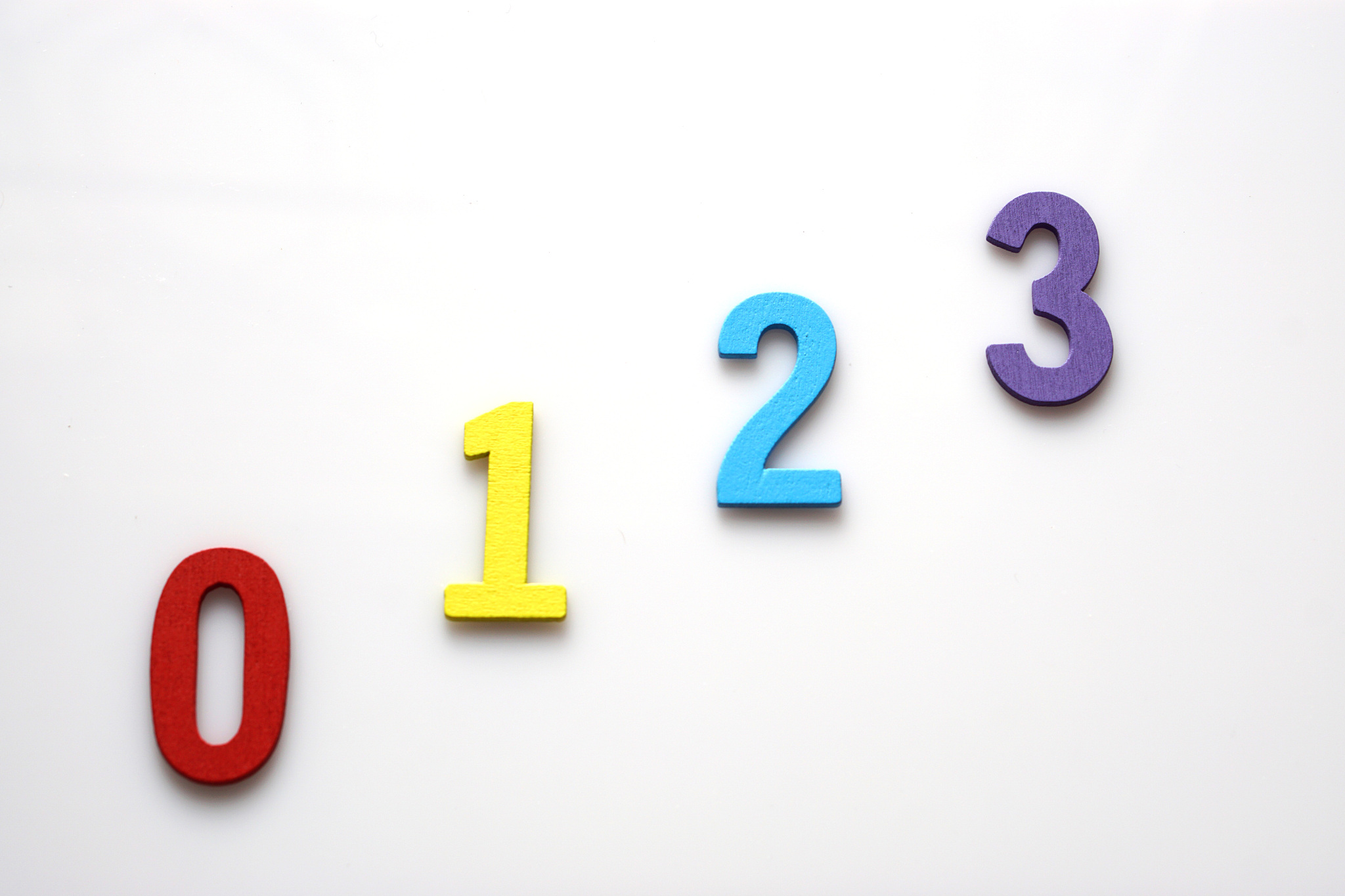 zero to three multicolored number letters  are lined on white ba
