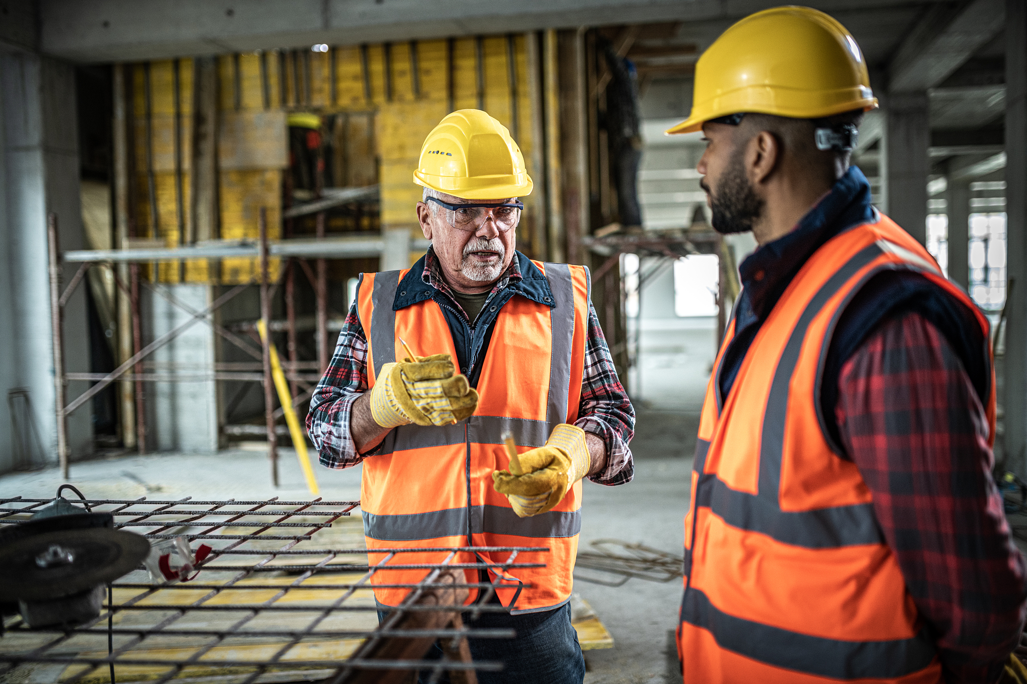 senior construction worker talking to younger colleague