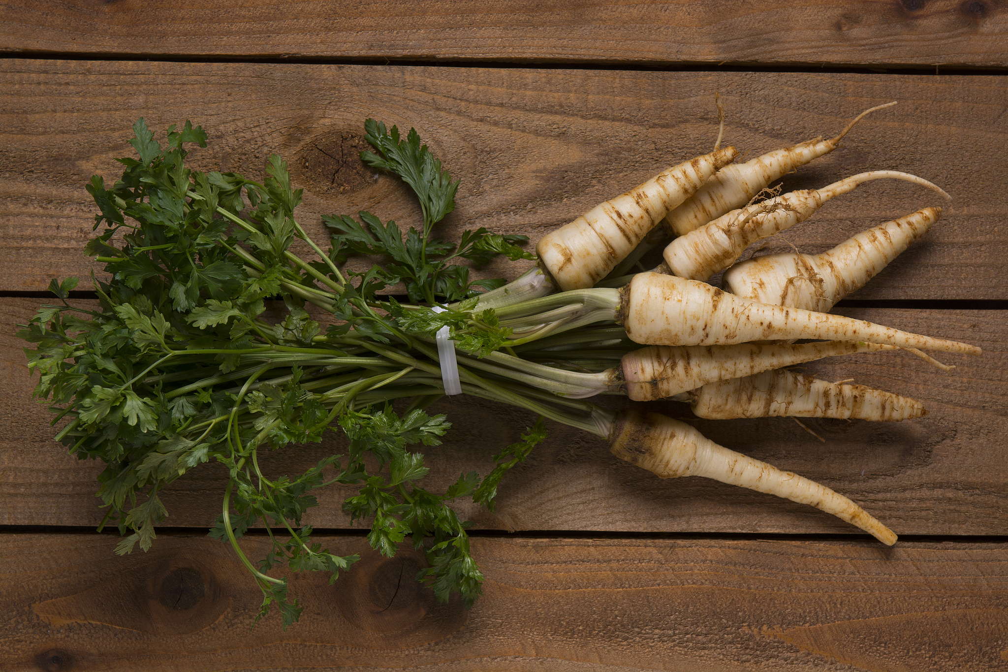parsley root with leaves  on a wood background.