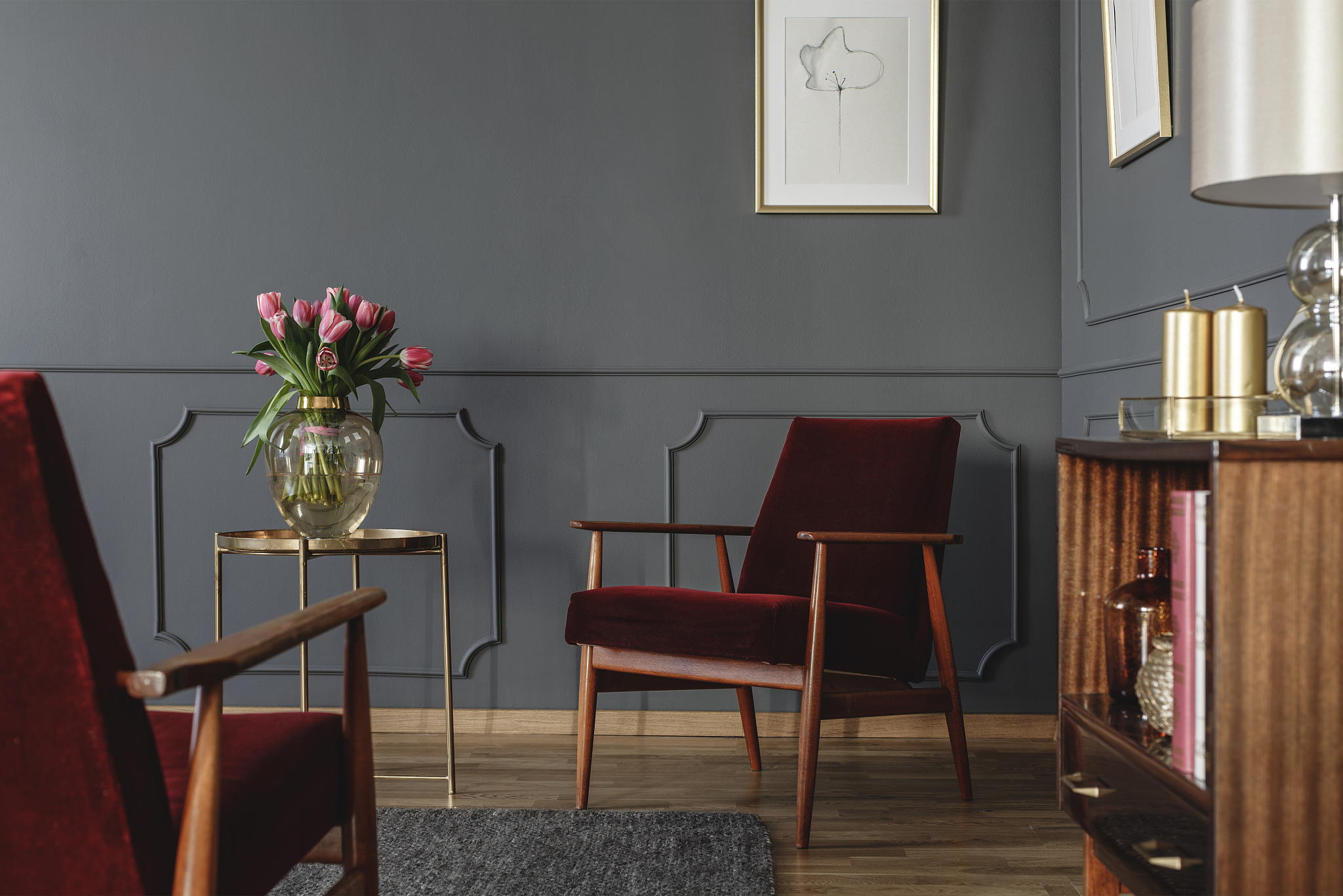 pink flowers on gold table next to red wooden armchair in dark l