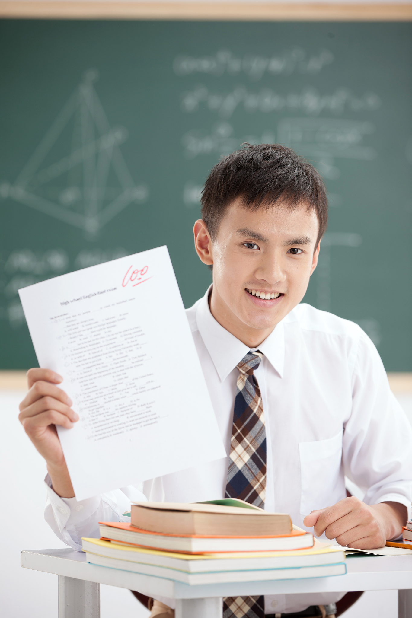 一个中学男生展示试卷在教室里