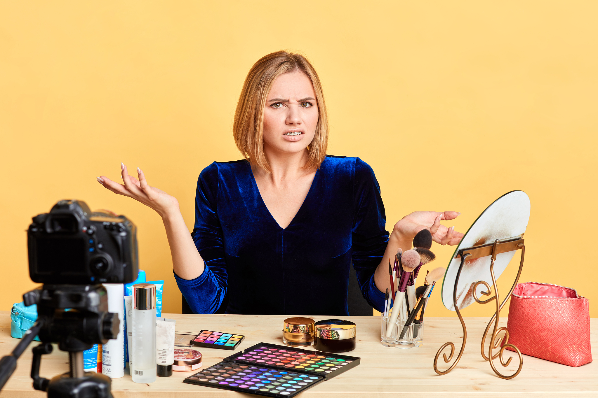 displeased female cosmetics expert spreads hands, frowns face in