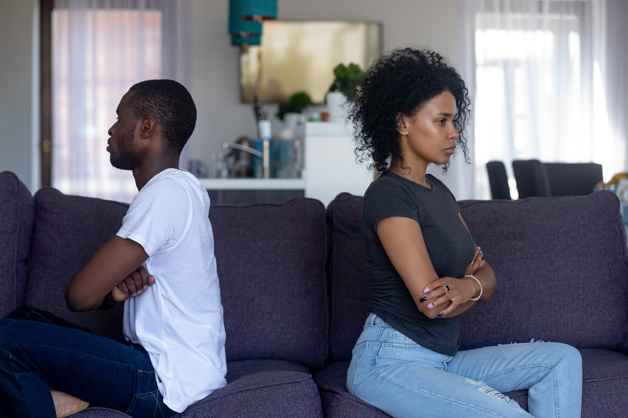 stubborn black couple sitting on couch ignoring each other