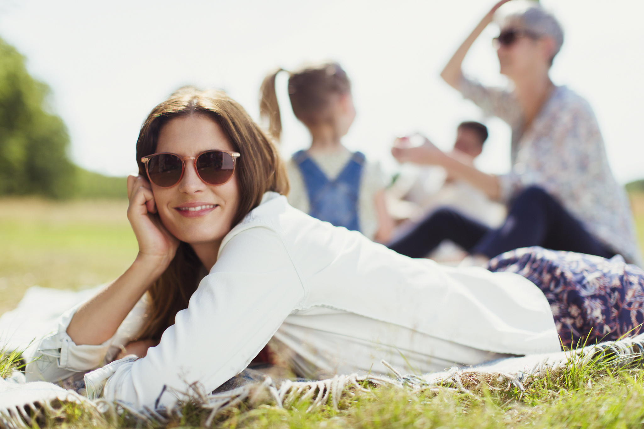 portrait smiling woman laying on blanket in sunny field