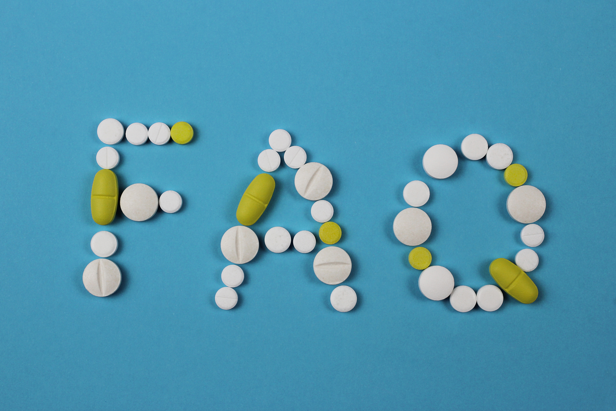 word faq made by white and yellow pills on blue background