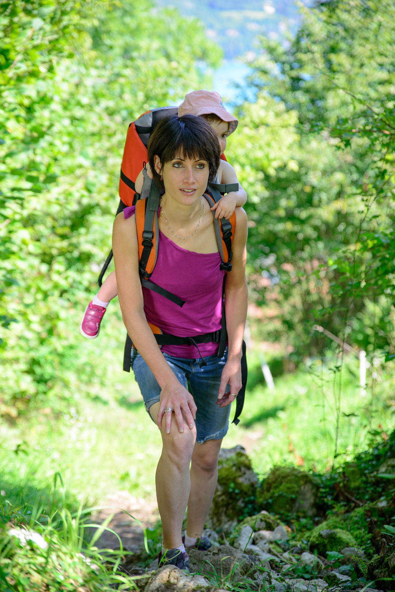 little girl in a baby carrier walks with his mom
