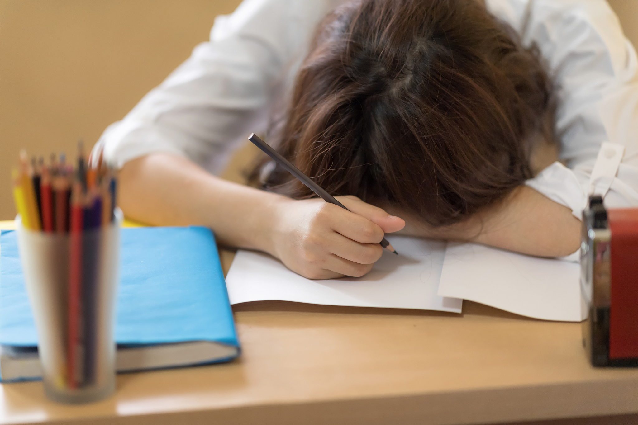 a tired and serious young student sleeping on notebook after rea