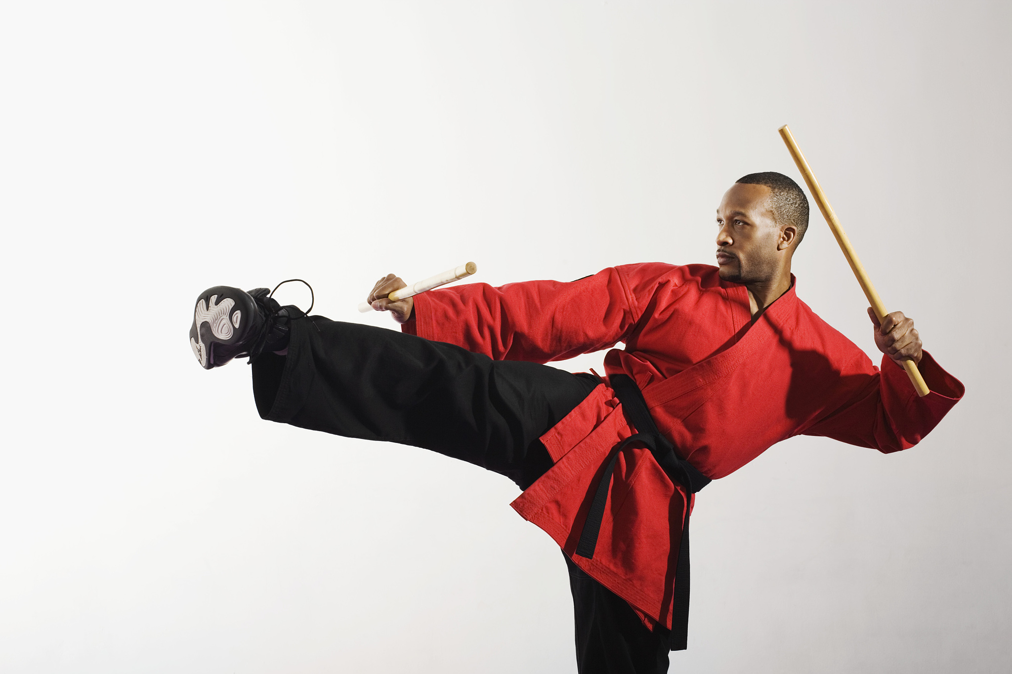 man doing side kick while holding sword