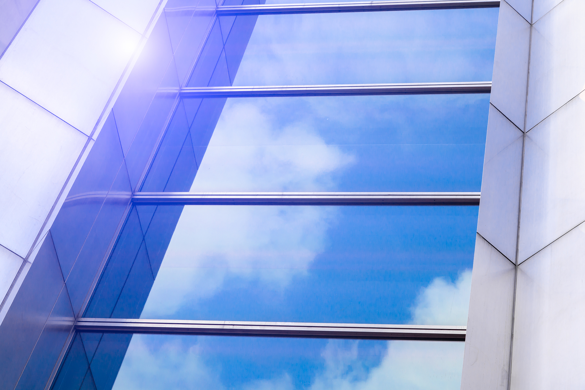 blue sky and clouds reflected in a modern glass facade