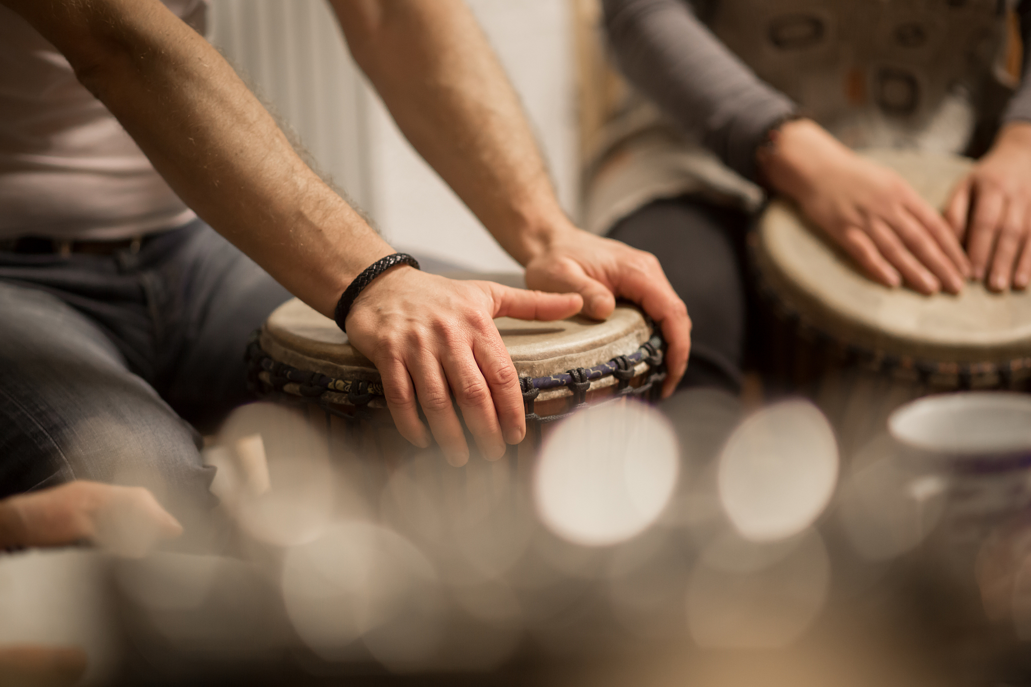 close up of hands on african drums, drumming for a music therapy