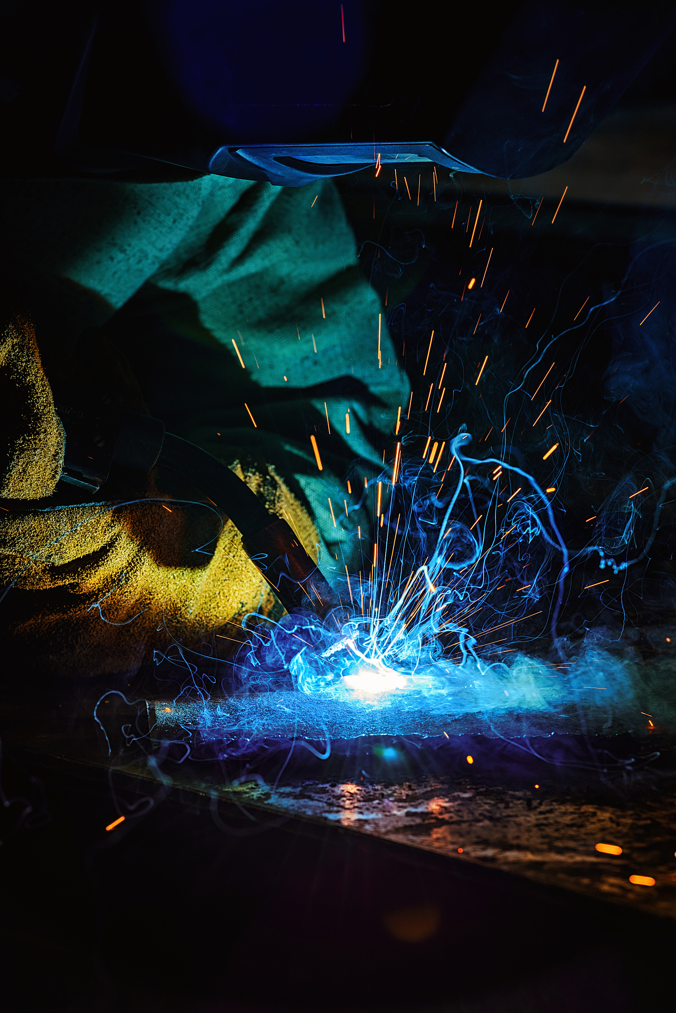 focused welder in protection mask brazing metal at factory