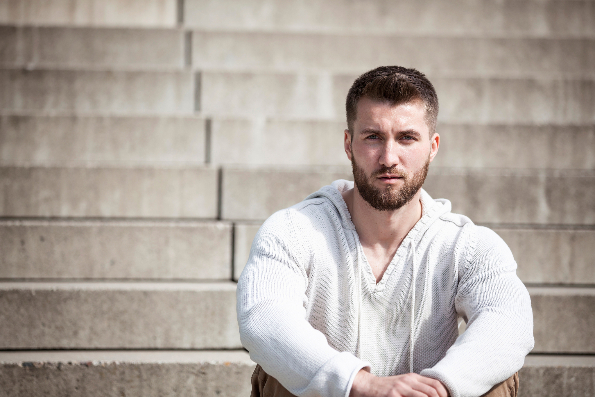 attractive man with a beard is sitting on steps
