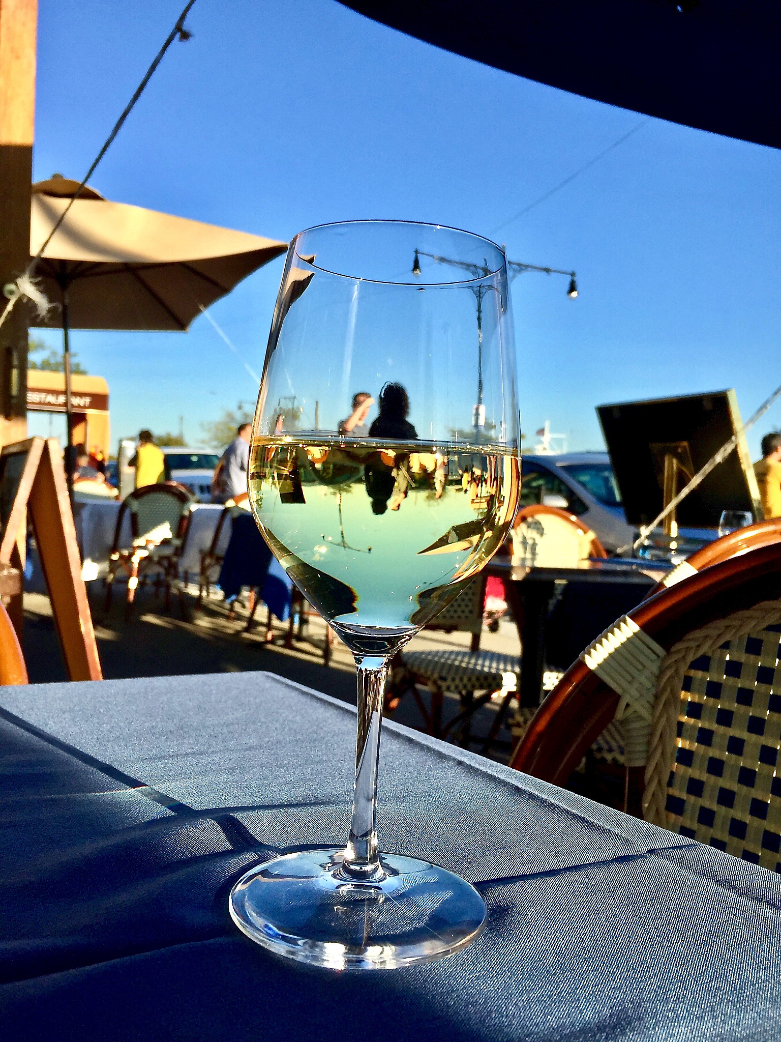 a glass of retsina wine on a table at an outdoor sidewalk restau
