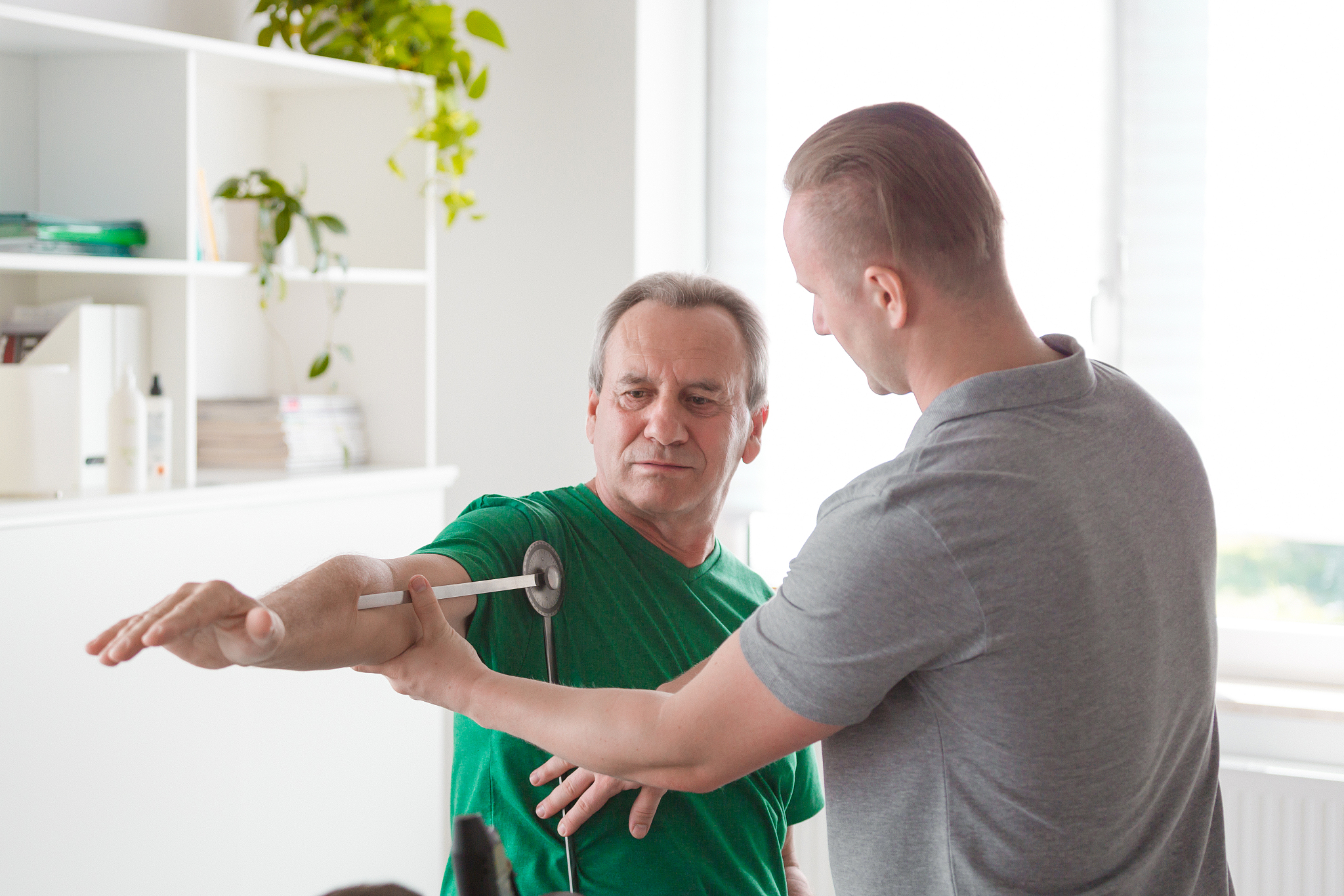 physiotherapist checking patient's shoulder with goniometer