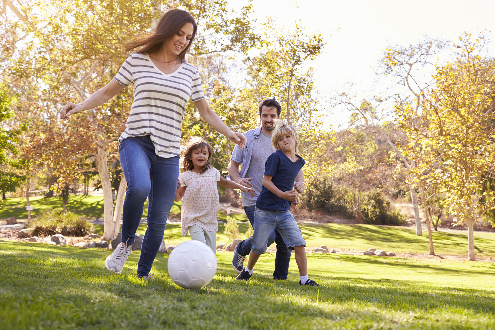 family playing soccer in park together