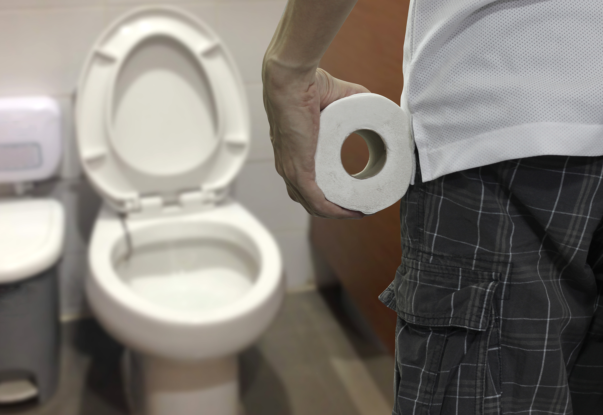 hand holding toilet paper roll and entering the toilet.