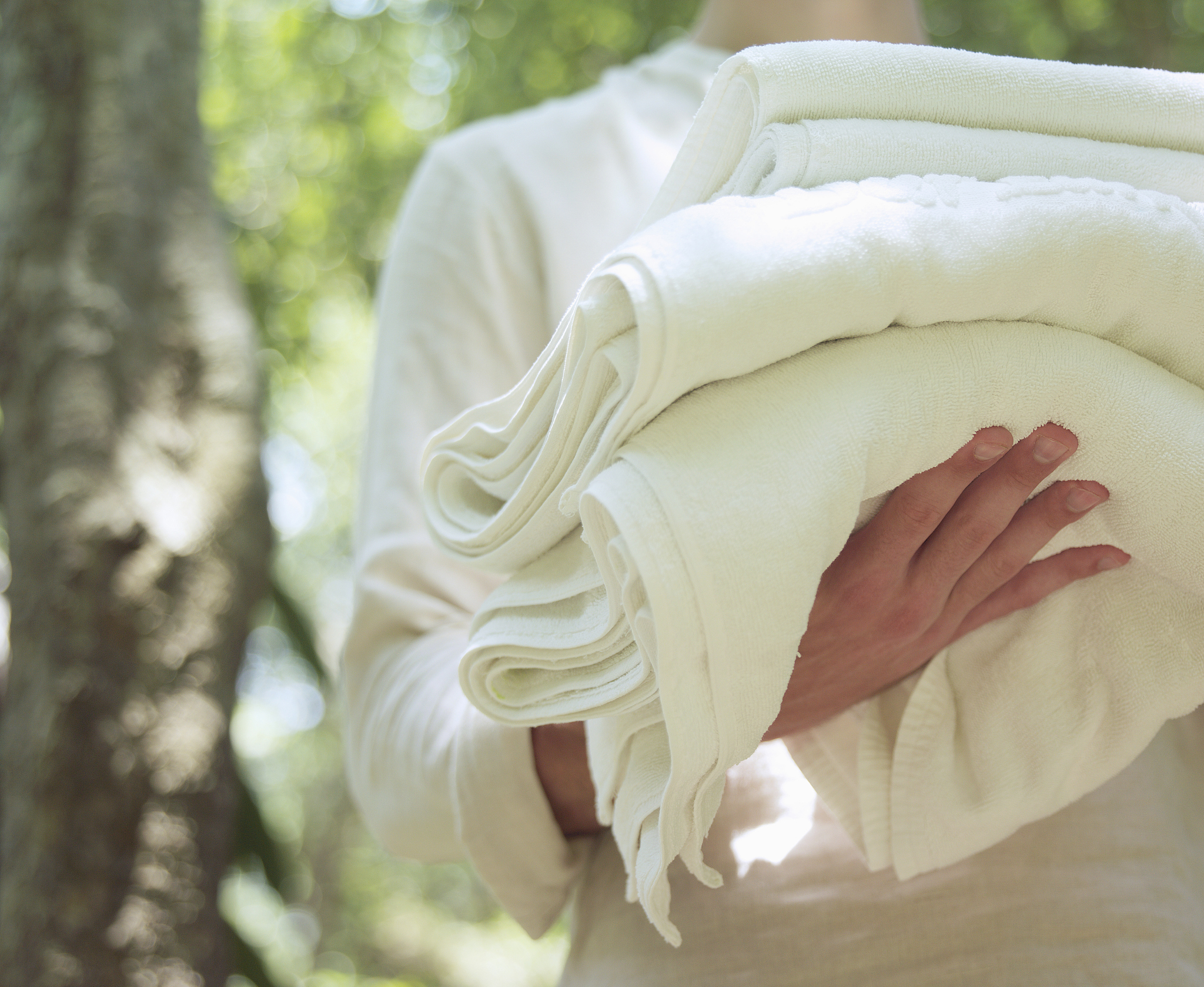 young man carrying pile of towels outdoors