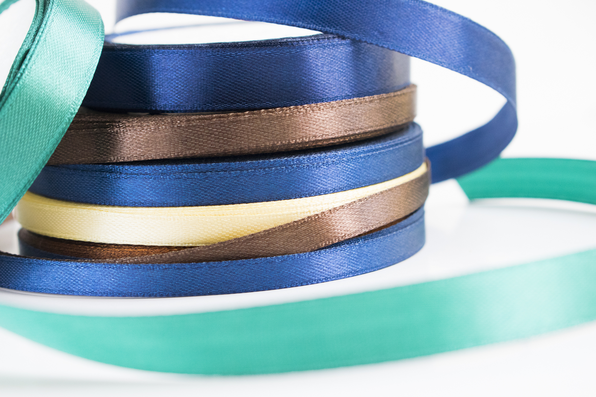 stack of satin ribbon coils. blue, green, brown and yellow ribbo