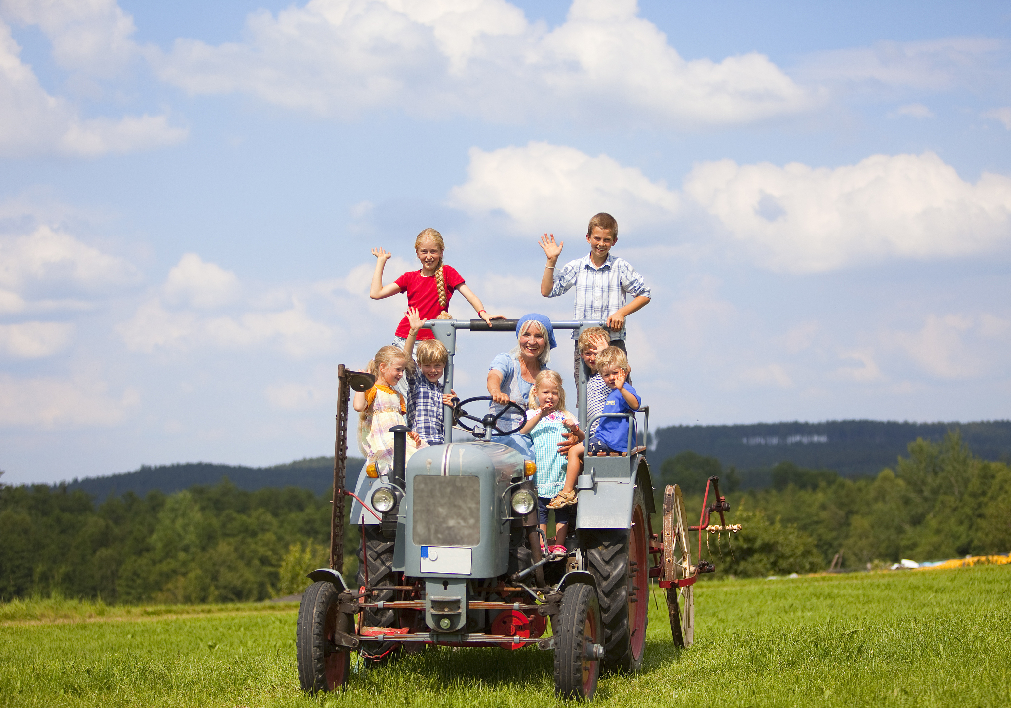germany, bavaria, woman with group of children sitting in old tr