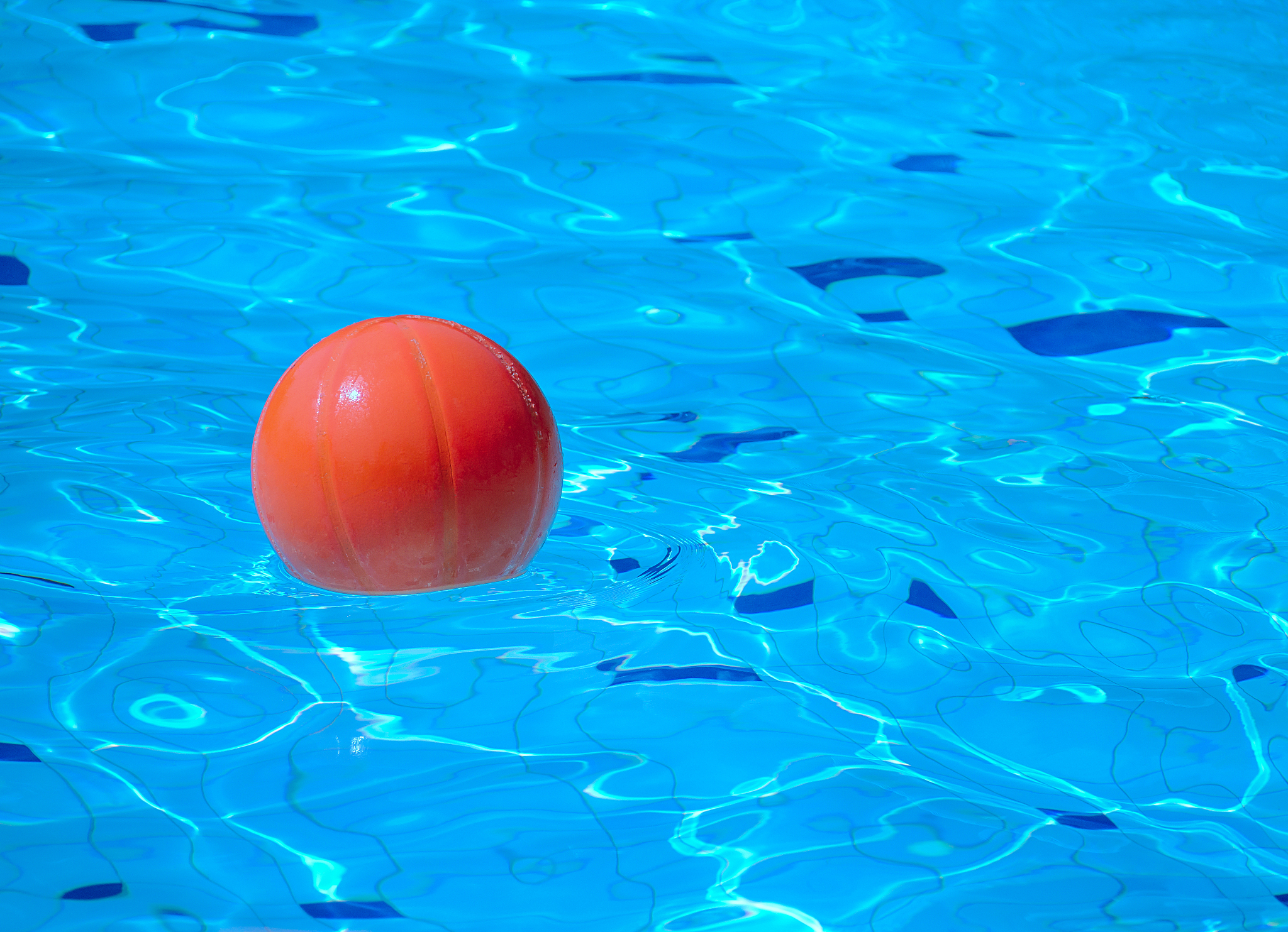 orange beach ball floating in blue swimming pool