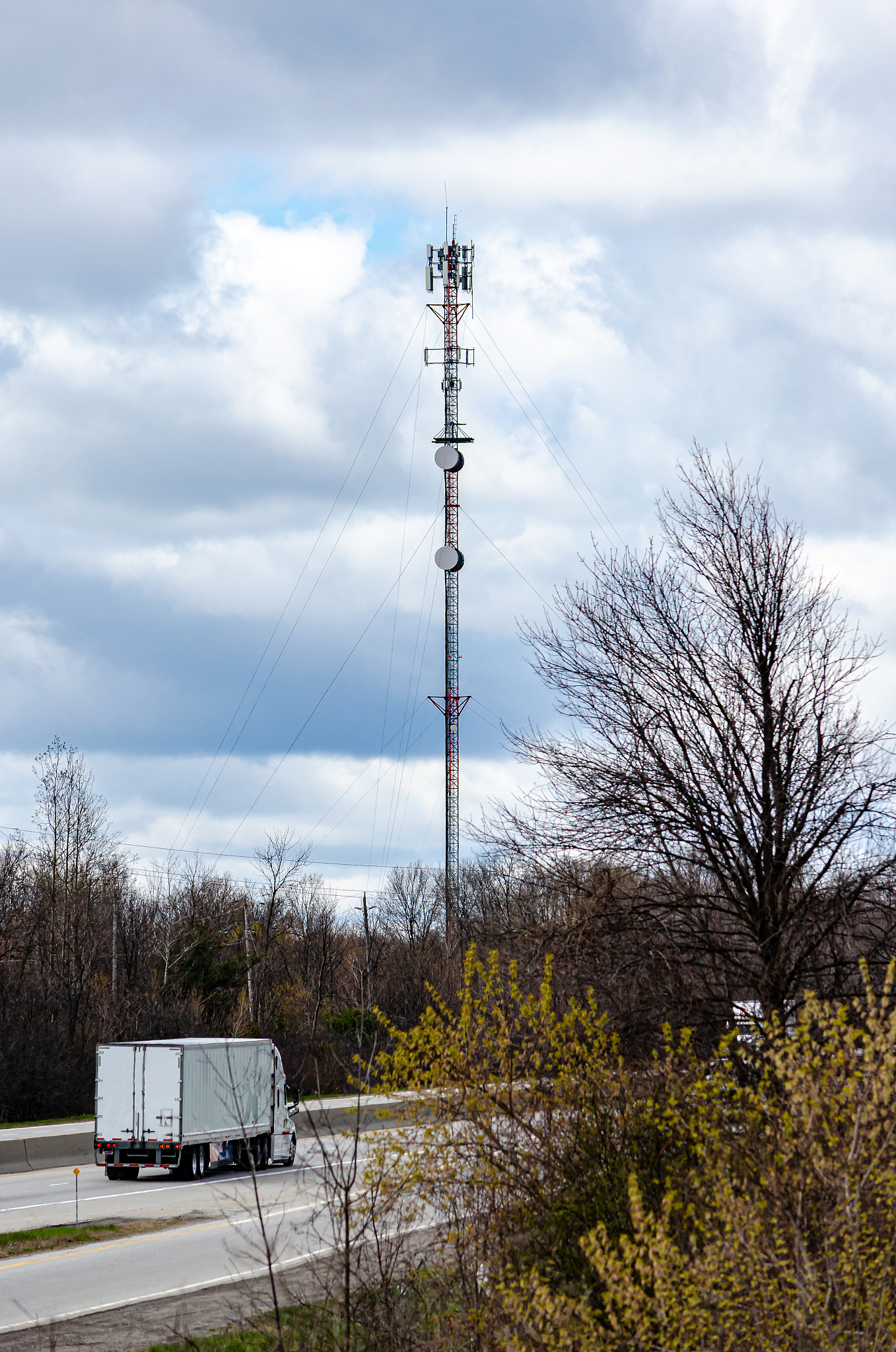 transport truck on highway next to a communication tower against
